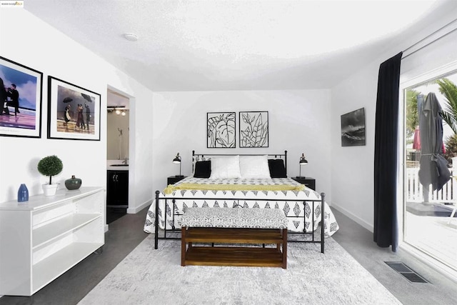 bedroom with concrete floors, a textured ceiling, and connected bathroom