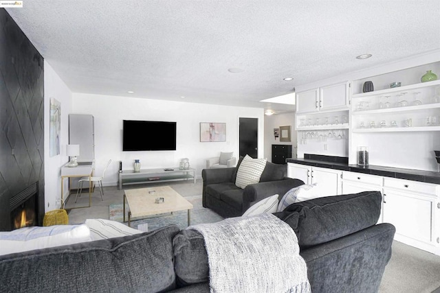 carpeted living room with a large fireplace, bar, and a textured ceiling