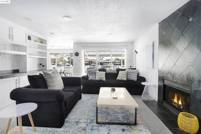 living room with a tile fireplace, built in features, and a textured ceiling