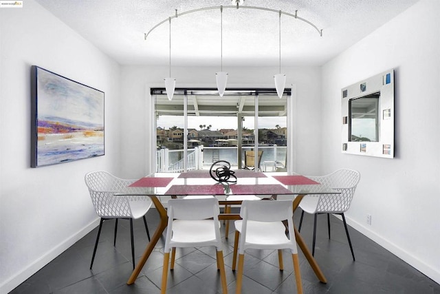 dining room with a textured ceiling and a water view