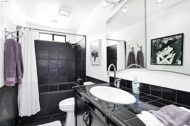 full bathroom with toilet, shower / tub combo with curtain, tile walls, tile patterned floors, and vanity