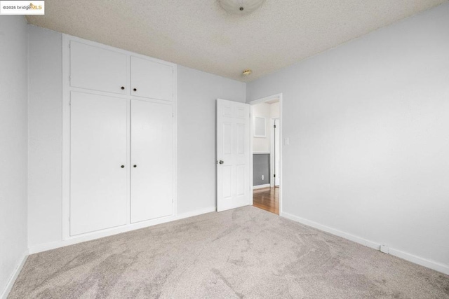 unfurnished bedroom featuring carpet flooring, a textured ceiling, and a closet