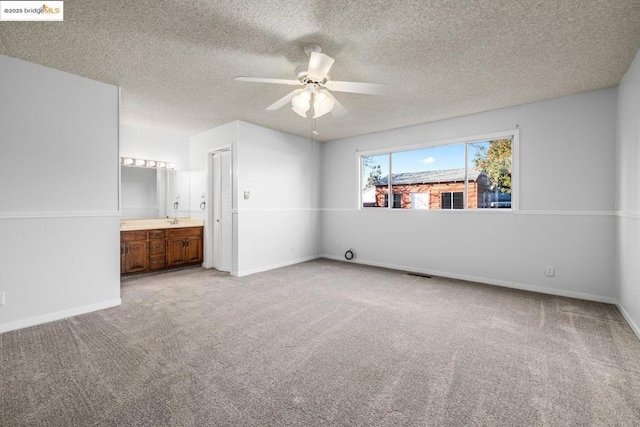 unfurnished bedroom with carpet flooring, connected bathroom, a textured ceiling, and ceiling fan