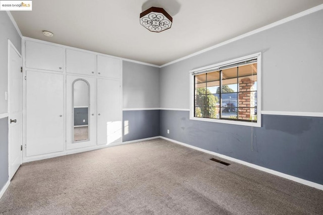 unfurnished bedroom with crown molding, carpet flooring, and a closet