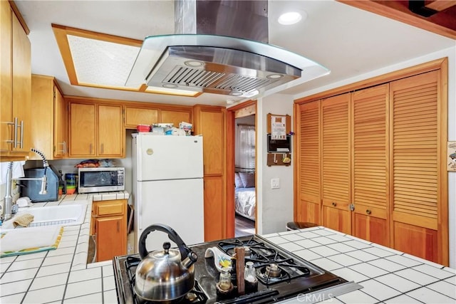 kitchen featuring island exhaust hood, tile countertops, white fridge, and stove