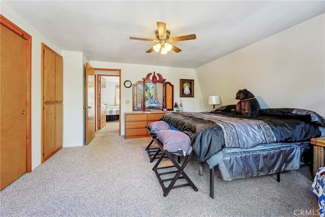 bedroom featuring multiple closets, light colored carpet, and ceiling fan