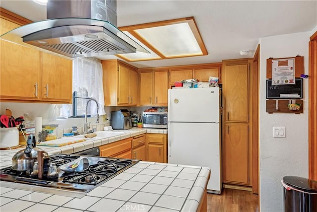 kitchen with sink, island range hood, tile countertops, and stainless steel appliances