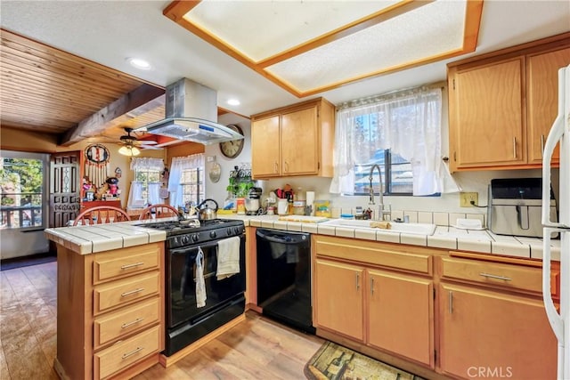 kitchen featuring tile countertops, black appliances, island exhaust hood, kitchen peninsula, and light hardwood / wood-style flooring