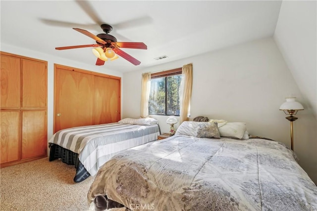 bedroom featuring two closets, vaulted ceiling, ceiling fan, and carpet