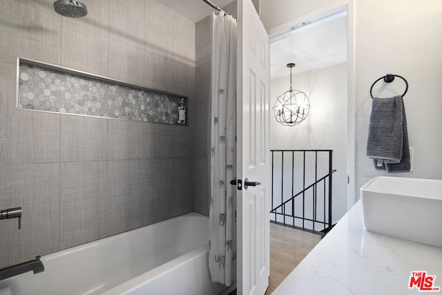 bathroom with wood-type flooring, shower / bath combo, sink, and an inviting chandelier