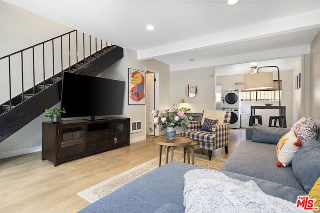 living room with light hardwood / wood-style floors, beamed ceiling, and stacked washer / drying machine