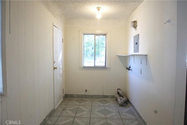 clothes washing area with wooden walls, electric panel, hookup for a washing machine, and a textured ceiling