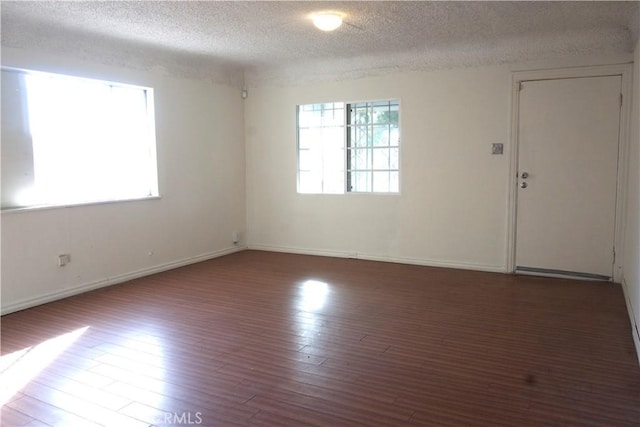 spare room with dark hardwood / wood-style flooring and a textured ceiling