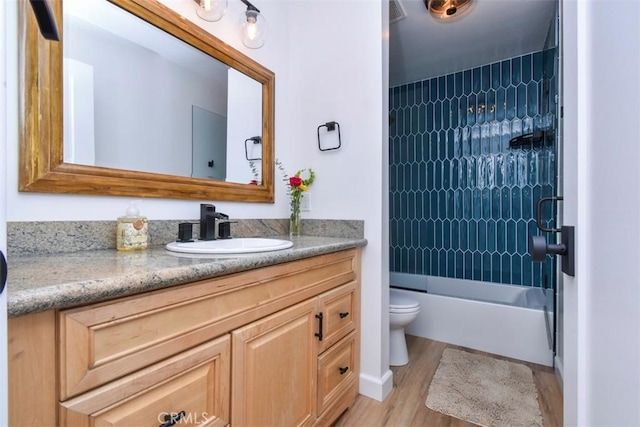 full bathroom with hardwood / wood-style floors, toilet, vanity, and tiled shower / bath