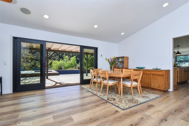 dining room featuring french doors, a healthy amount of sunlight, light hardwood / wood-style floors, and lofted ceiling