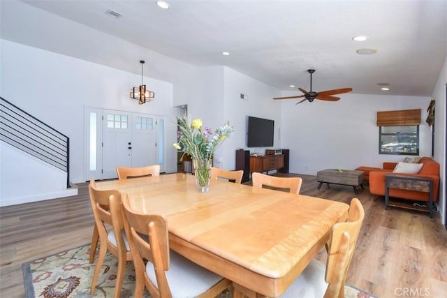 dining space featuring hardwood / wood-style floors, ceiling fan with notable chandelier, and lofted ceiling