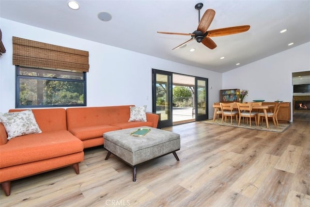 living room featuring light hardwood / wood-style floors, lofted ceiling, and ceiling fan