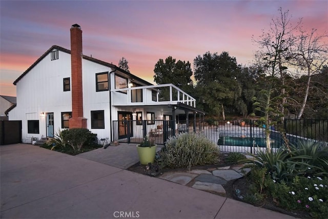 view of front of home featuring a balcony, a fenced in pool, and a patio