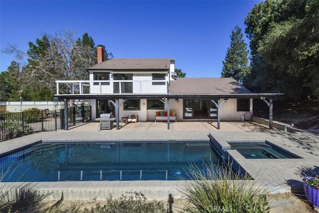 back of property with a balcony, a patio, and a swimming pool with hot tub