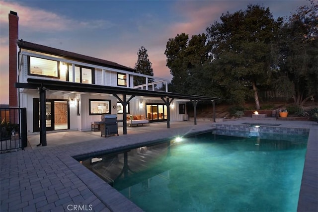 pool at dusk featuring a patio area