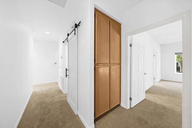 hallway featuring light carpet and a barn door