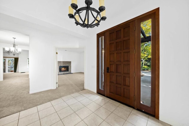 entryway featuring a notable chandelier, a premium fireplace, and light colored carpet