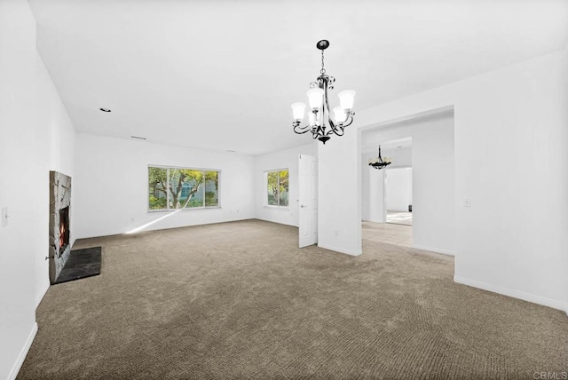 unfurnished living room with light carpet, a chandelier, and a stone fireplace