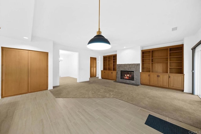 unfurnished living room featuring built in shelves, light colored carpet, and a fireplace