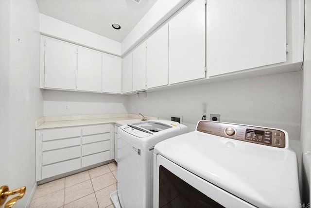 washroom with sink, cabinets, light tile patterned floors, and separate washer and dryer