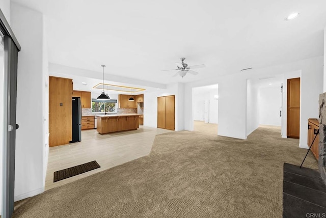 unfurnished living room with light carpet and ceiling fan