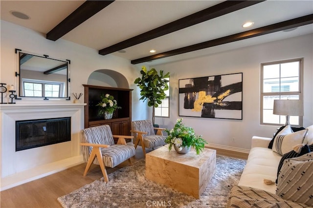 living room featuring light wood-type flooring, beamed ceiling, and a wealth of natural light