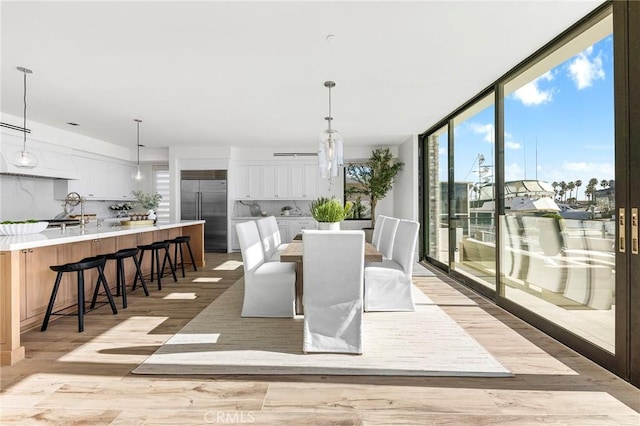 dining space with floor to ceiling windows, light hardwood / wood-style flooring, and a notable chandelier