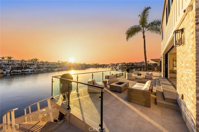 dock area featuring a water view and an outdoor living space with a fire pit