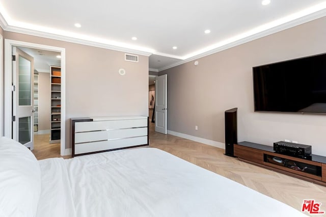 bedroom with light parquet floors, a spacious closet, and ornamental molding