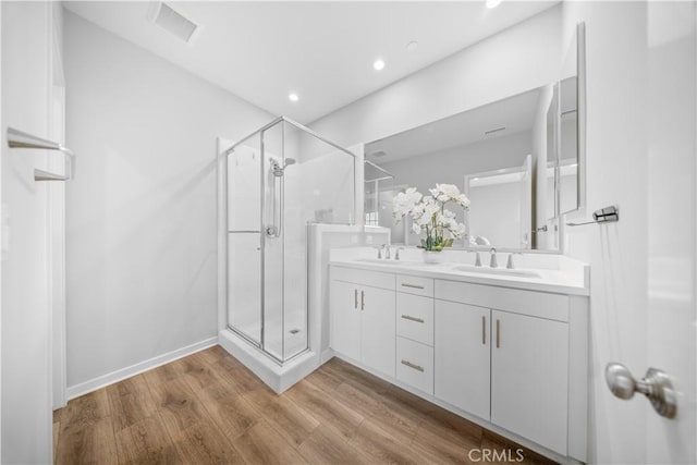 bathroom with wood-type flooring, walk in shower, and vanity