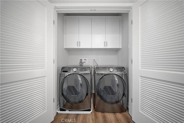 laundry room featuring wood-type flooring, independent washer and dryer, and cabinets