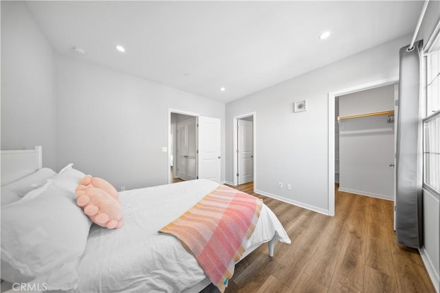 bedroom featuring a walk in closet, hardwood / wood-style flooring, and a closet