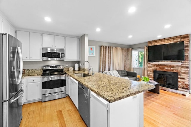 kitchen featuring sink, stainless steel appliances, light stone counters, white cabinets, and kitchen peninsula