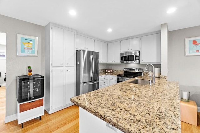 kitchen with appliances with stainless steel finishes, sink, white cabinets, and kitchen peninsula