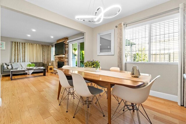 dining space featuring a fireplace, light hardwood / wood-style floors, and a wealth of natural light