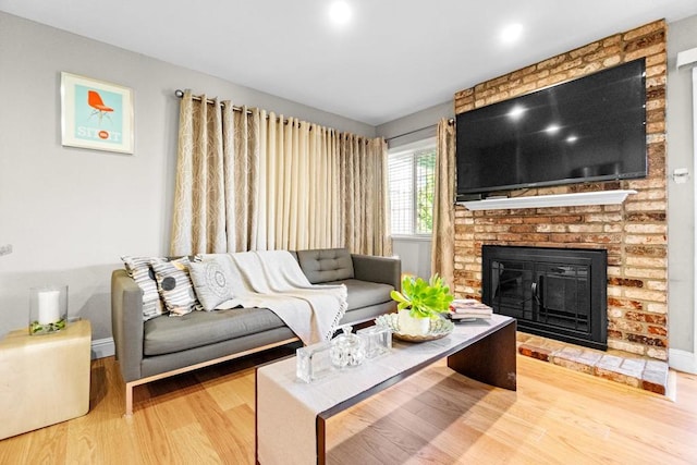 living room with hardwood / wood-style flooring and a brick fireplace