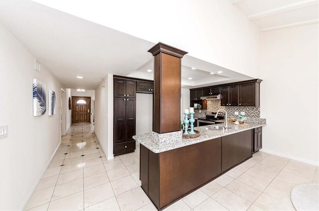 kitchen featuring kitchen peninsula, dark brown cabinets, stainless steel range with electric stovetop, and light stone countertops