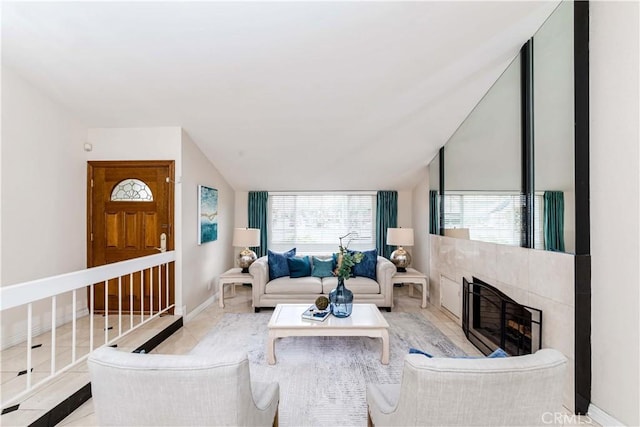 living room featuring a tile fireplace, plenty of natural light, and lofted ceiling