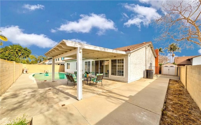 back of property with central AC unit, a patio area, and a fenced in pool