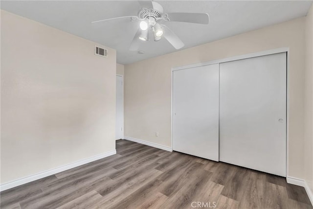 unfurnished bedroom featuring hardwood / wood-style floors, ceiling fan, and a closet