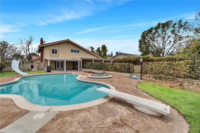 view of swimming pool with a water slide, a patio area, a diving board, and an in ground hot tub