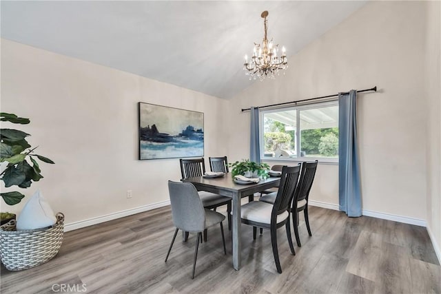 dining room with hardwood / wood-style flooring, an inviting chandelier, and vaulted ceiling