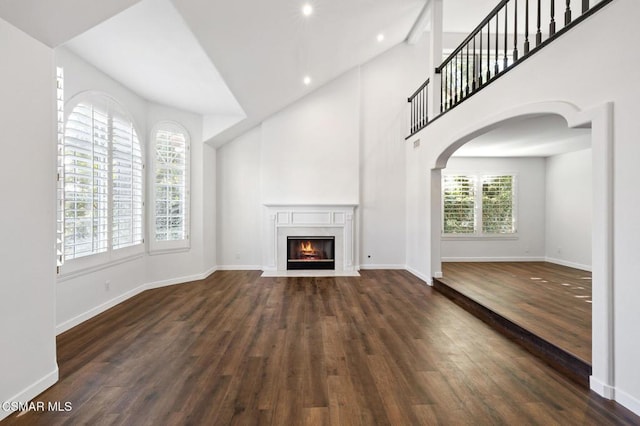 unfurnished living room with dark hardwood / wood-style floors and a towering ceiling