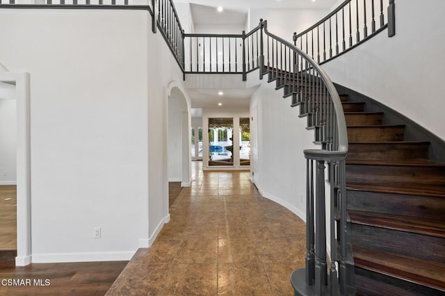 foyer entrance with tile patterned flooring and a towering ceiling