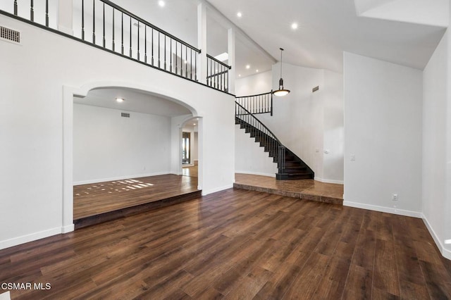 unfurnished living room featuring dark hardwood / wood-style flooring and a high ceiling